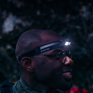 Zijkant profiel van een man die de zwarte BioLite HeadLamp 440 draagt, de lamp is aan en werpt licht opzij, duidelijke pasvorm.