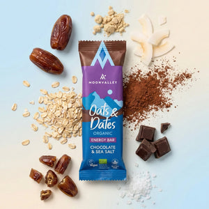 Moonvalley Oats and Dates Chocolate and Sea Salt biologische energy bar omringd door haver, dadels, cacaopoeder, chocoladeblokjes en zeezout