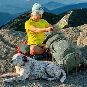 Osprey Ariel 65 groene dames trekkingrugzak in gebruik tijdens een hike in de natuur met een kaart en hond