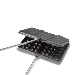 Gietijzeren Petromax wafelijzer met lange stelen, houten handgrepen en een wafelpatroon voor het bakken van verse wafels boven open vuur.