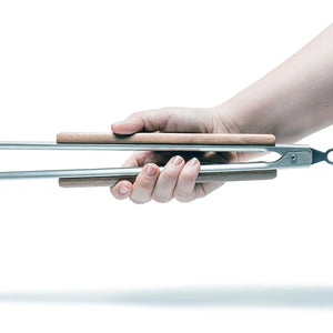 Petromax RVS barbecuetang klein model met een houten handgreep, golvende kop en sluitmechanisme voor outdoor grillen.