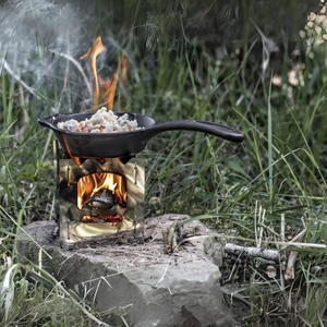 Een zwarte Petromax gietijzeren koekenpan van 20 cm op een barbecue rooster tijdens een outdoor maaltijd.
