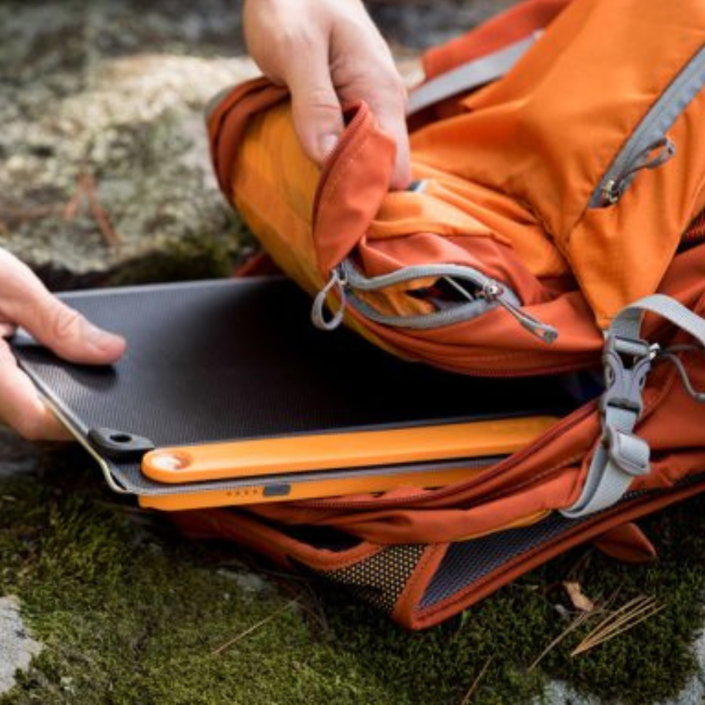 Goal Zero Nomad opvouwbaar draagbaar zonnepaneel in oranje behuizing dat uit een rugzak wordt gehaald