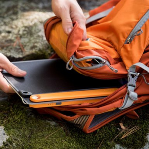 Goal Zero Nomad opvouwbaar draagbaar zonnepaneel in oranje behuizing dat uit een rugzak wordt gehaald