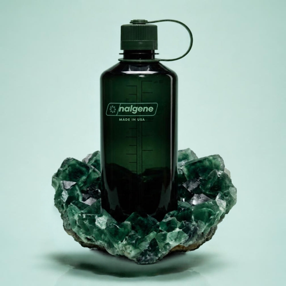 Nalgene Wide-Mouth waterfles 1000ml donkergroen staand op een groene minerale kristallen formatie   