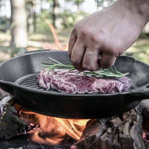 Gietijzeren Petromax grill skillet van 35 cm met een geribbelde bodem voor grillstrepen en handige schenktuiten aan de zijkanten.