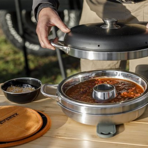 Driedelige roestvrijstalen Petromax camping oven met een ringvormige bakvorm en deksel voor het bakken op kampeerkooktoestellen.
