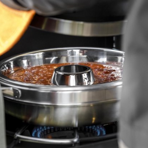 Driedelige roestvrijstalen Petromax camping oven met een ringvormige bakvorm en deksel voor het bakken op kampeerkooktoestellen.