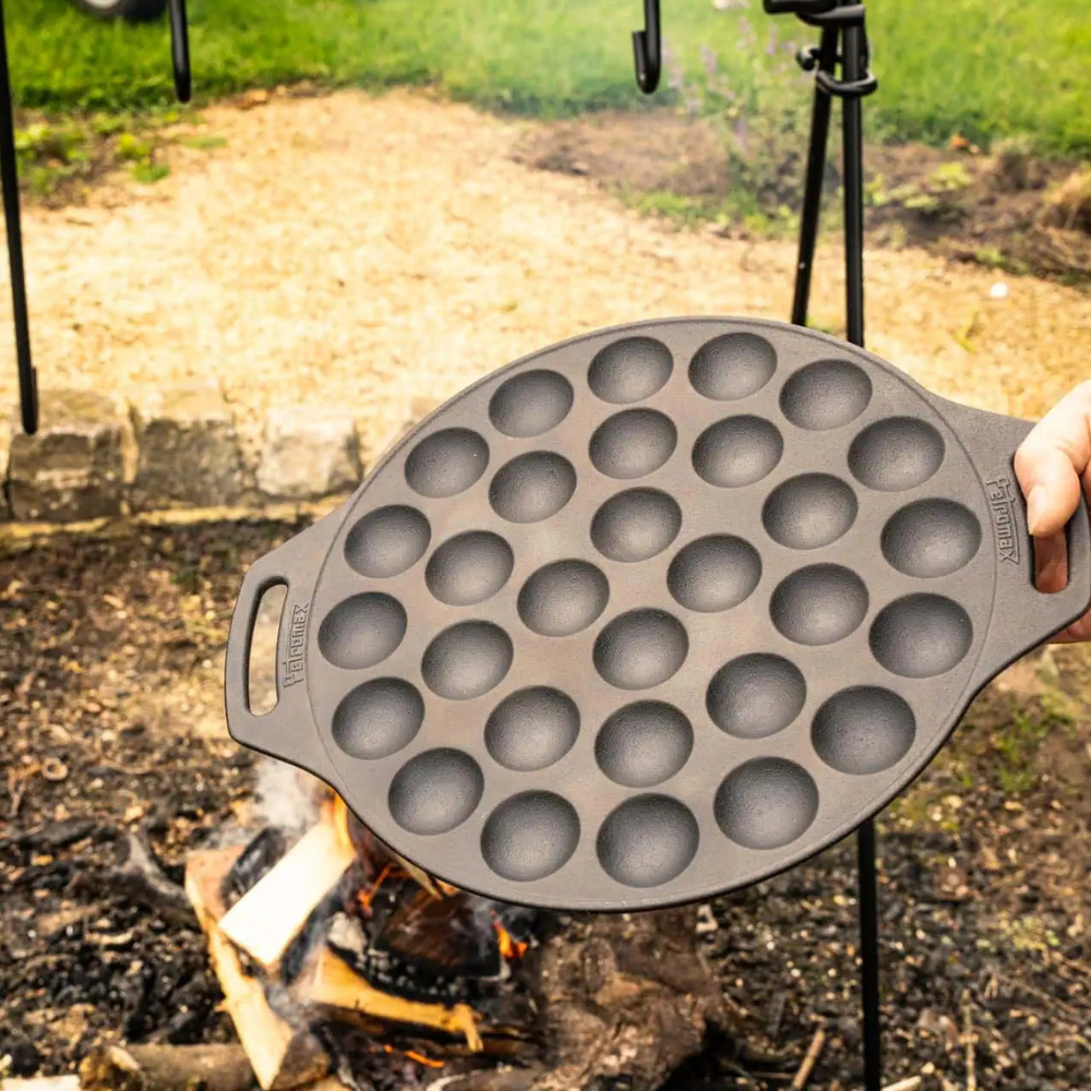 Ronde gietijzeren Petromax poffertjespan met een vlakke bodem en twee handgrepen voor het bakken van 30 poffertjes op open vuur.