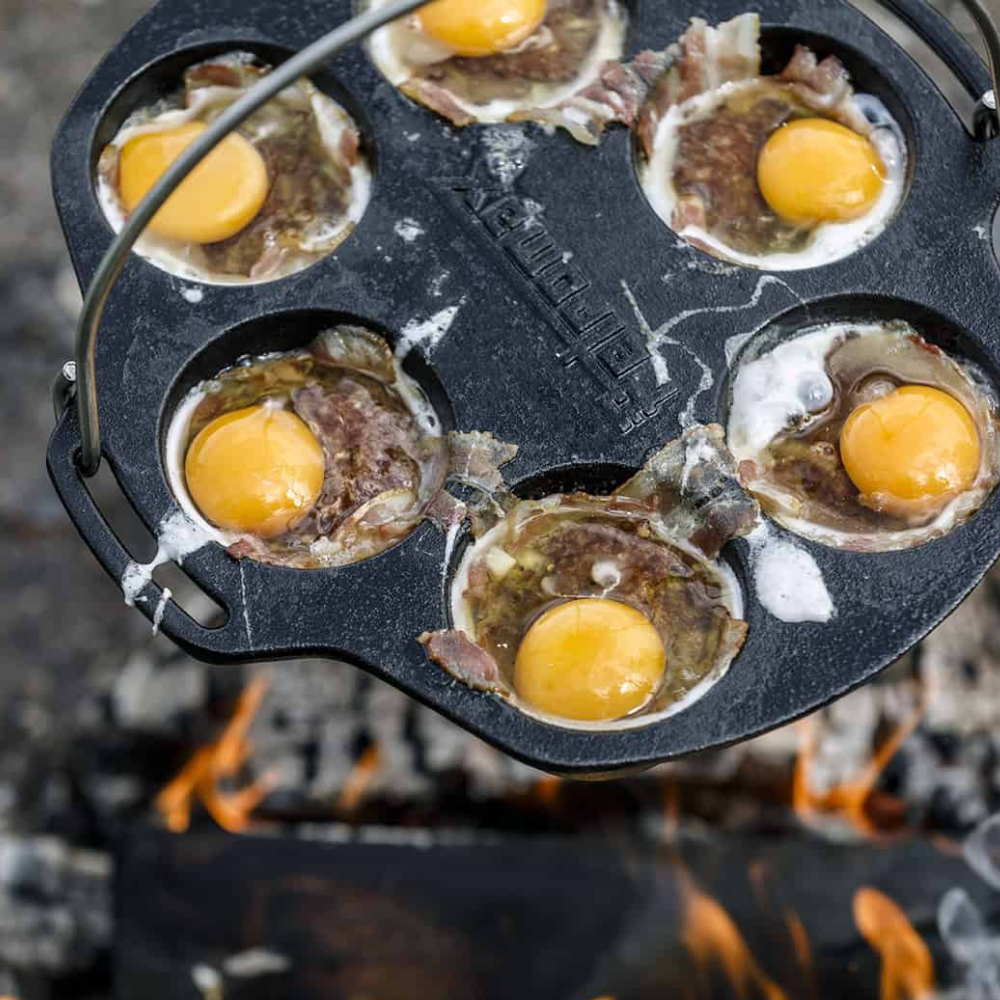 Gietijzeren Petromax mf6 muffinvorm met 6 inkepingen en een metalen draagbeugel voor het bakken van muffins boven open vuur.