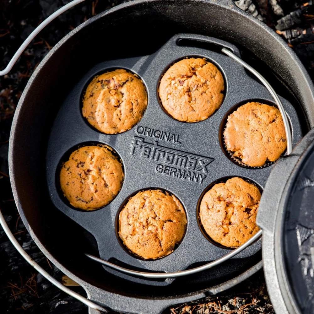 Gietijzeren Petromax mf6 muffinvorm met 6 inkepingen en een metalen draagbeugel voor het bakken van muffins boven open vuur.