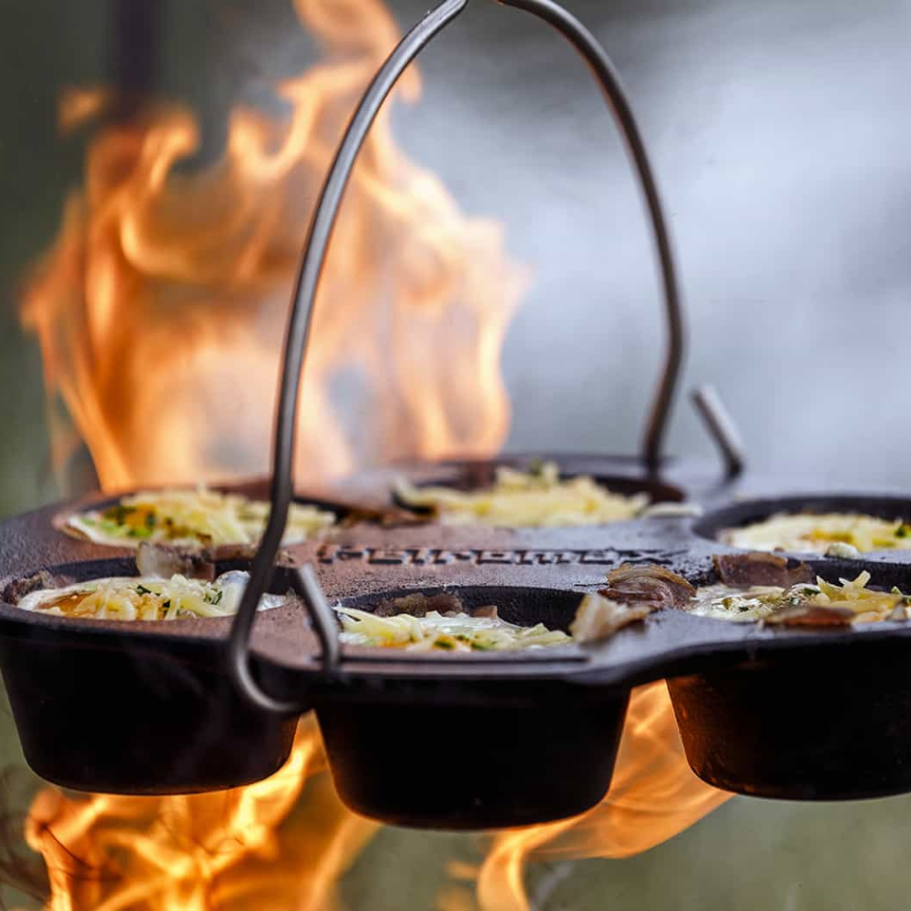 Gietijzeren Petromax mf6 muffinvorm met 6 inkepingen en een metalen draagbeugel voor het bakken van muffins boven open vuur.